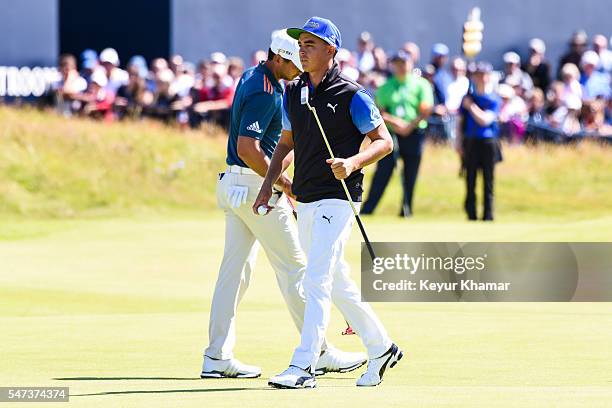 Rickie Fowler of the United States waves his putter to fans after putting on the 18th hole green during the first round on day one of the 145th Open...