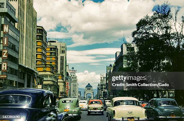 Cars drive through the streets of Mexico City, with Cine Prado, the Hotel Regis, and several advertising signs visible, Mexico City, Mexico, 1952. .