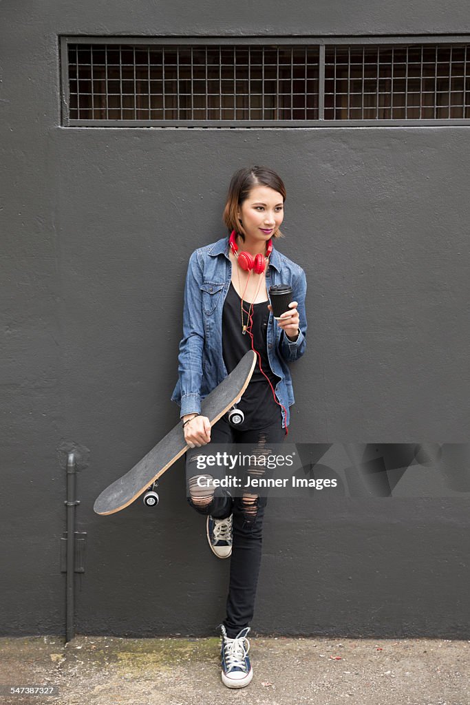 Young Asian woman holding skateboard