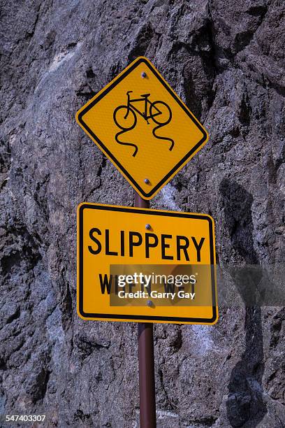 slippery when wet sign on hill side - slippery road sign stock pictures, royalty-free photos & images