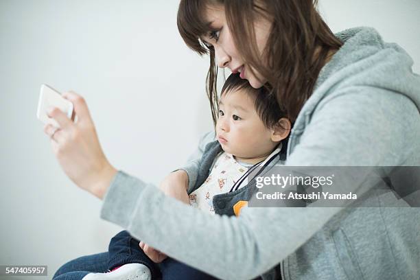 asian mother and baby taking picture of themselves - capturar una imagen fotografías e imágenes de stock