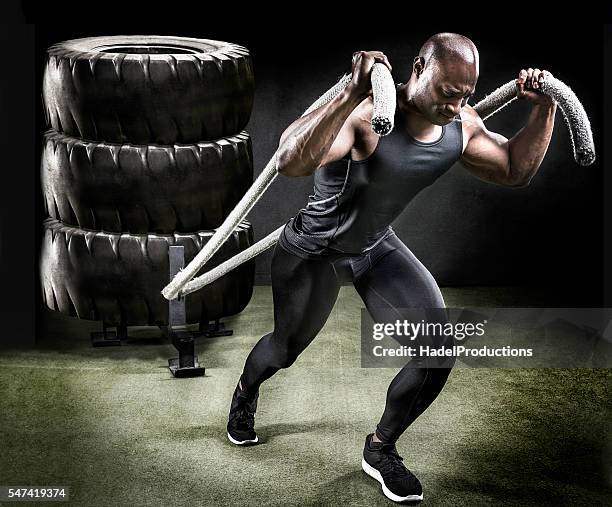 muscular athlete pulling sled of tires. - pulling stockfoto's en -beelden