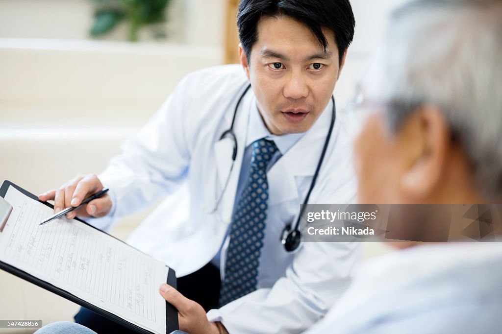 Male doctor showing record and explaining senior patient