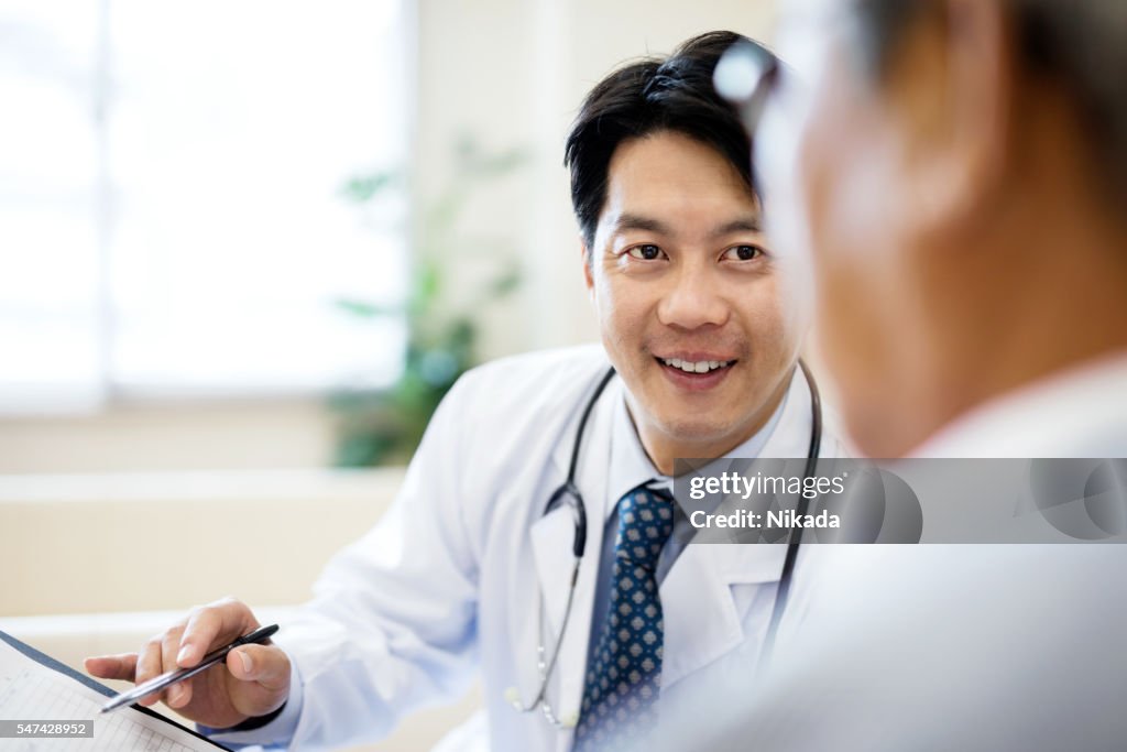 Male doctor showing record and explaining senior patient