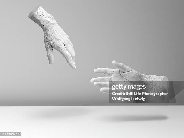 two white hands in an abstract space, one hand tries to reach the other hand for help - helping hand stock-fotos und bilder