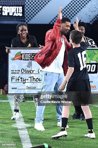Host Russell Wilson and $50K Triple Shot contestant Oliver Callanan react during a contest onstage during the Nickelodeon Kids' Choice Sports Awards...