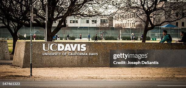 The UC Davis logo with a soccer game and bike riders in the background. University of California at Davis. Davis, California. Taken February 2, 2015.