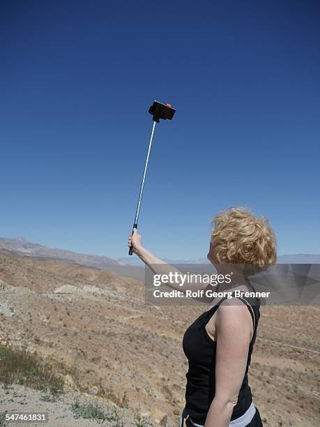 Woman using selfie stick in the desert