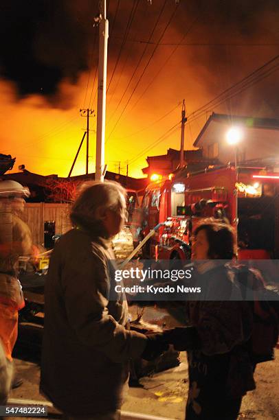 Japan - People console each other near burning houses in Iwaki, Fukushima Prefecture, northeastern Japan, on March 11 after a major earthquake.