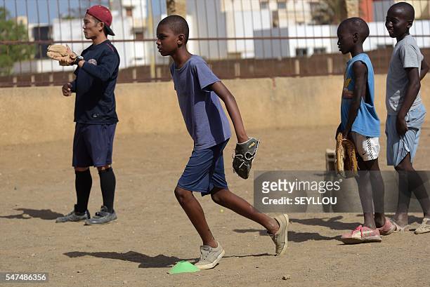 Picture taken on July 13, 2016 shows Japanese aid worker Ryoma Ogawa playing baseball with young Senegalese children on an improvised baseball pitch...