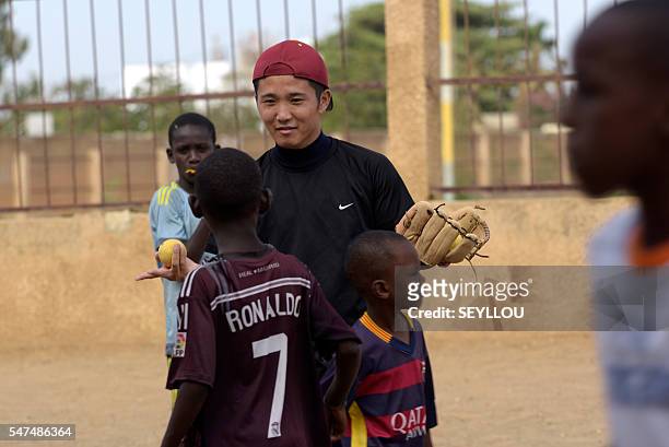 Picture taken on July 14, 2016 shows Japanese aid worker Ryoma Ogawa playing baseball with young Senegalese children on an improvised baseball pitch...