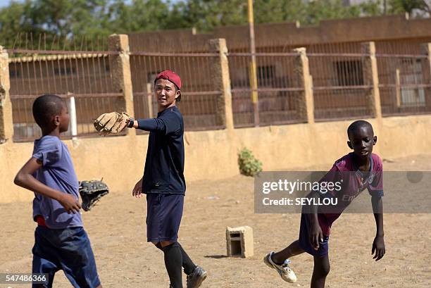 Picture taken on July 13, 2016 shows Japanese aid worker Ryoma Ogawa playing baseball with young Senegalese children on an improvised baseball pitch...