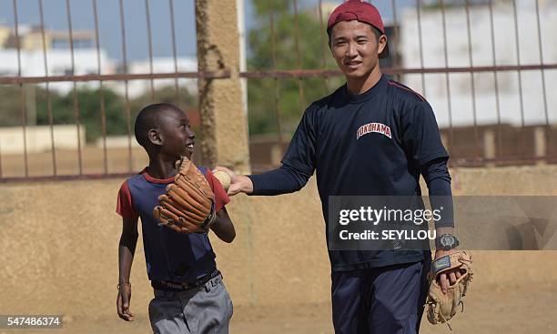 Picture taken on July 13, 2016 shows Japanese aid worker Ryoma Ogawa playing baseball with young Senegalese children on an improvised baseball pitch...