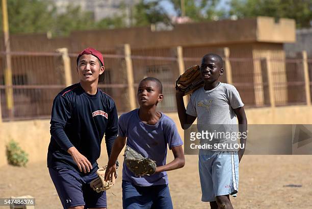 Picture taken on July 13, 2016 shows Japanese aid worker Ryoma Ogawa playing baseball with young Senegalese children on an improvised baseball pitch...