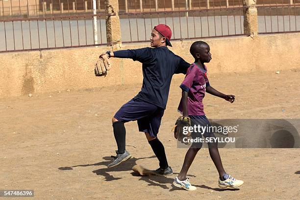 Picture taken on July 13, 2016 shows Japanese aid worker Ryoma Ogawa playing baseball with young Senegalese children on an improvised baseball pitch...