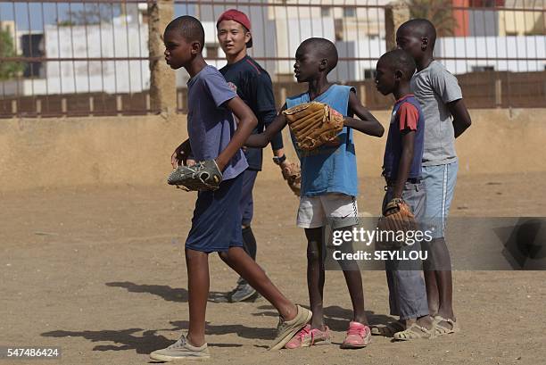 Japanese aid worker Ryoma Ogawa plays baseball on July 13, 2016 with young Senegalese children on an improvised baseball pitch in the impoverished...