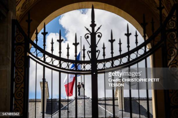 Picture taken through the gate shows French Republican guards placing the French flag at half-staff at the Elysee presidential Palace, in Paris, on...