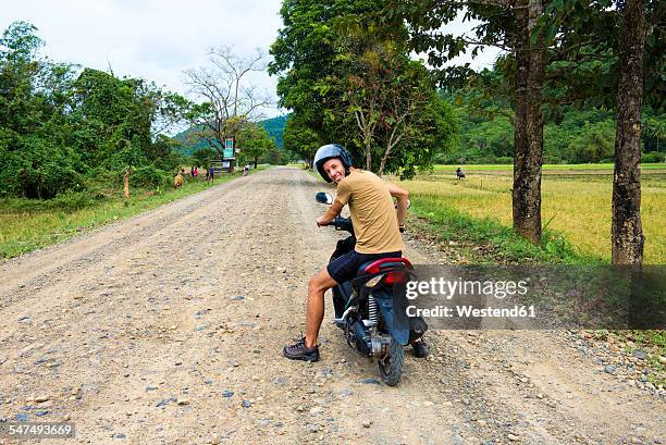 philippines, palawan island, man driving a motorcycle on a dirt road near el nido - on the move rear view stockfoto's en -beelden