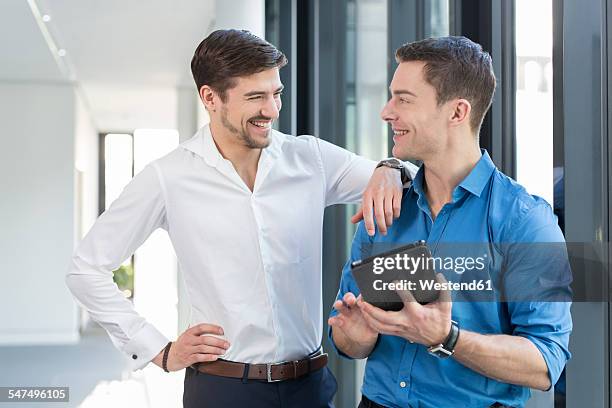 two businessmen with digital tablet in an office - nebeneinander-stehen stock-fotos und bilder