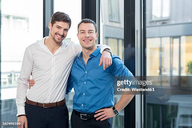 two businessmen side by side in an office - arm umlegen stock-fotos und bilder