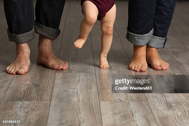 father, mother and baby girl standing barefoot on floor - baby standing stock pictures, royalty-free photos & images