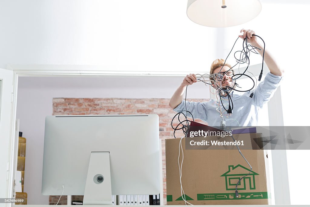 Young man with cable tangle in office