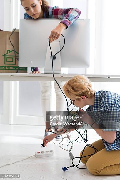 two young women in office connecting computer screen - power strip stock pictures, royalty-free photos & images