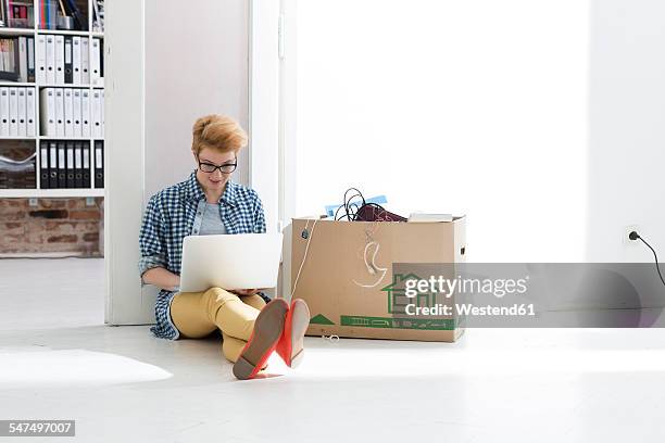 young woman sitting on floor in office using laptop next to cardboard box - makeshift office stock pictures, royalty-free photos & images