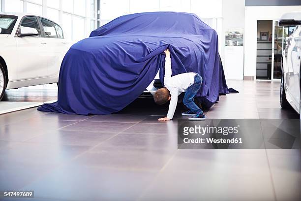 boy at car dealer unveiling tarpaulin - launch party inside stock-fotos und bilder