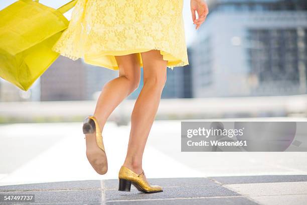 yellow dressed woman with golden shoes and shopping bag - robe jaune photos et images de collection