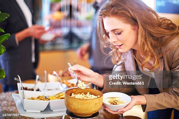 businesswoman taking cashews from breakfast buffet - lunch photos et images de collection