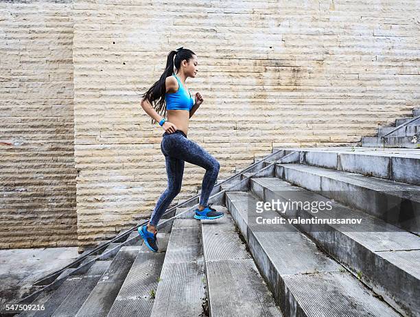 female runner moving up on stone stairs-side view - clambering imagens e fotografias de stock