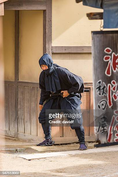 stealthy japanese ninja sneaking through a traditional village - militante gruppe stock-fotos und bilder
