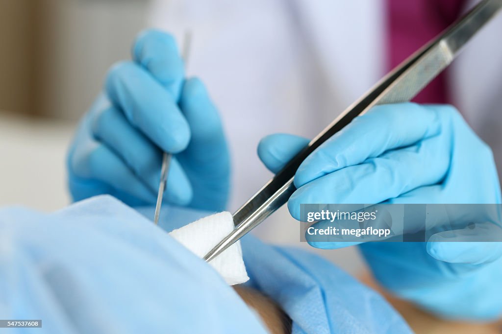 Surgeon hand hold scalpel and tweezers