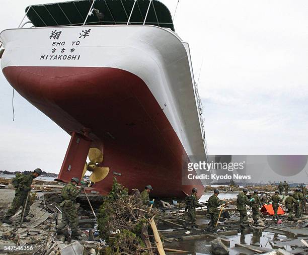 Japan - Members of the Japan Self-Defense Forces search for survivors and victims around a big ship moved by a tsunami in Higashimatsushima, Miyagi...