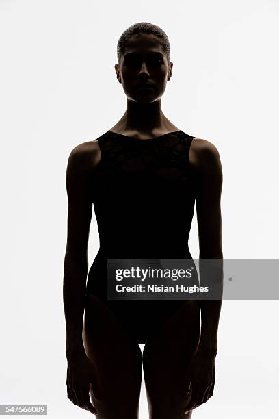 portrait of woman backlit looking at camera - dark background light stock-fotos und bilder