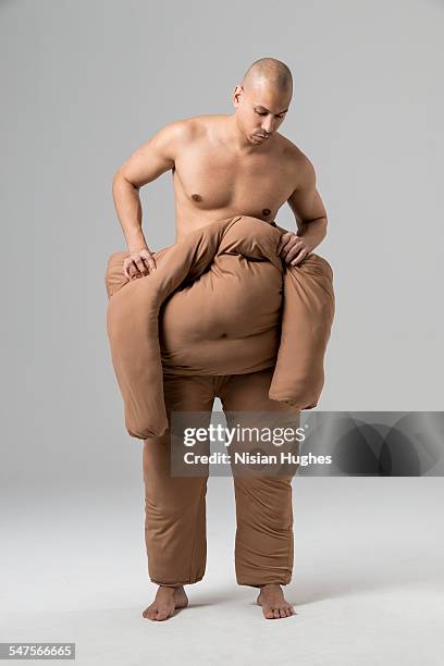 man pushing off fat suit - spogliarsi foto e immagini stock