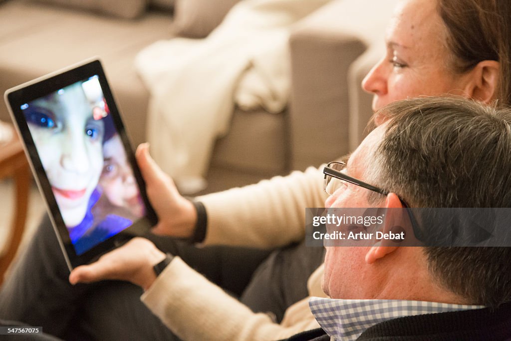 Family with grandparents doing Facetime with tablet computer.
