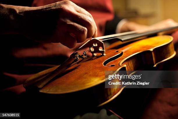 violin maker tuning an instrument, close-up - violin stock pictures, royalty-free photos & images