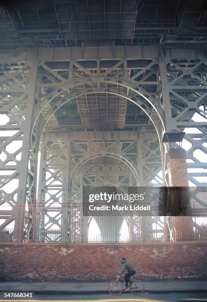 man on bicycle passing under williamsburg bridge - 威廉斯堡 布碌侖 個照片及圖片檔