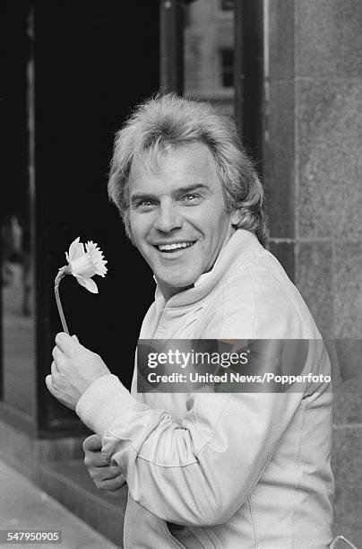 English comedian and singer, Freddie Starr pictured holding a daffodil in London on 17th March 1983.