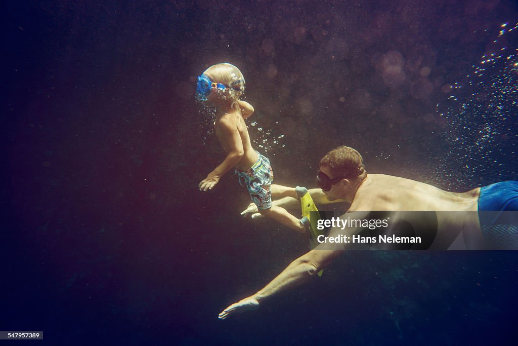 Man snorkeling with boy in the sea, underwater vie