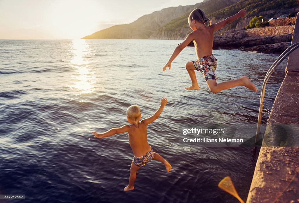 Two boys jumping into sea