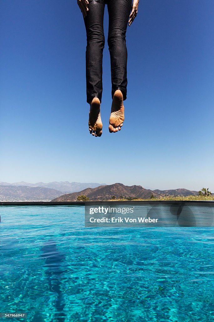 Woman jumping into pool seen from behind