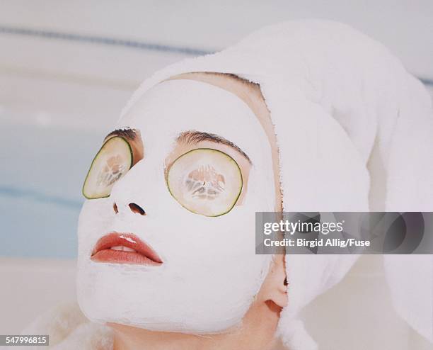 young woman wearing facial cream with cucumber slices over eyes - cucumber eye mask stock pictures, royalty-free photos & images