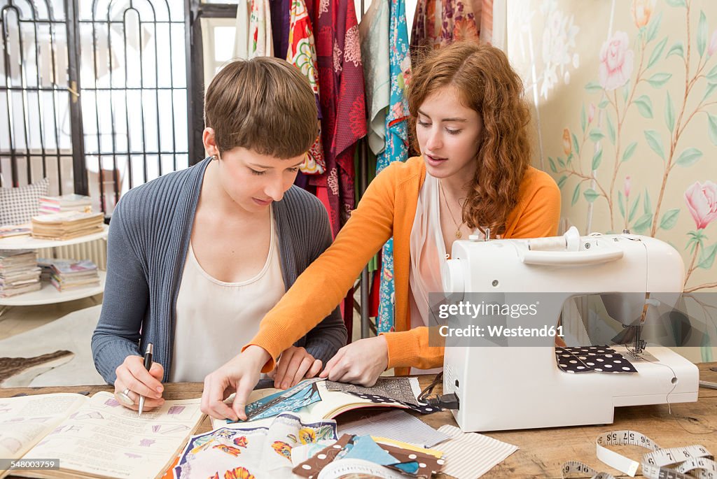 Two female fashion designers working together at their studio