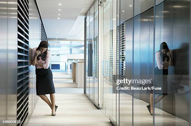 businesswoman on cell phone in hallway - downlight stock pictures, royalty-free photos & images