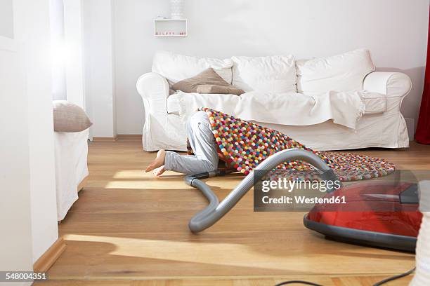 boy in living room hoovering under carpet - stofzuiger stockfoto's en -beelden
