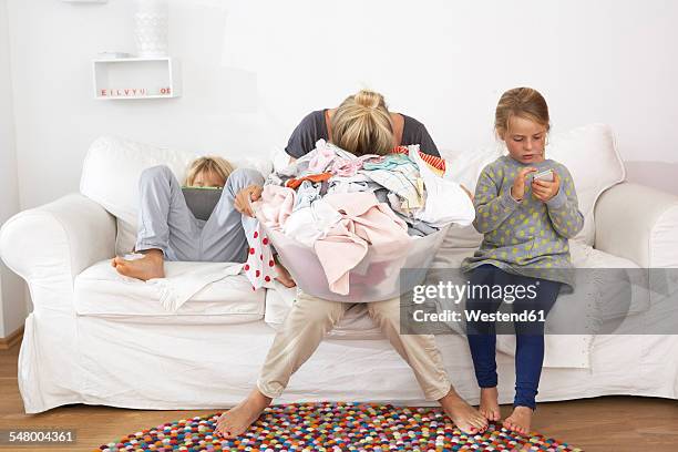 exhausted mother with laundry basket on couch with children using digital tablet and cell phone - laundry basket fotografías e imágenes de stock