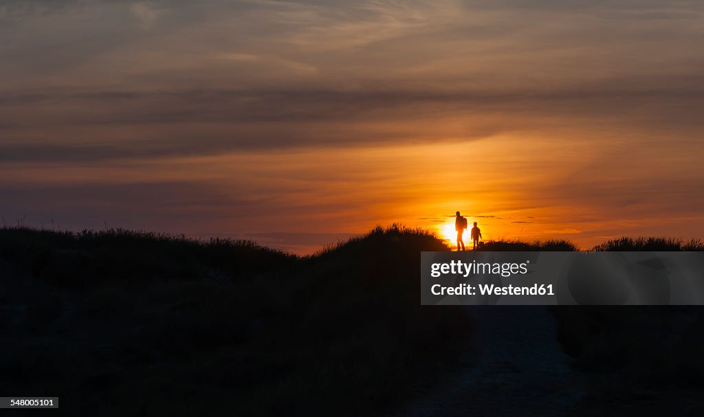 Denmark, Jutland, Lokken, mother and daughter walking in dune at sunset